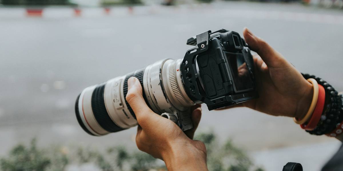 Photographer using a nature photography lens to capture misty mountain ridge at sunrise
