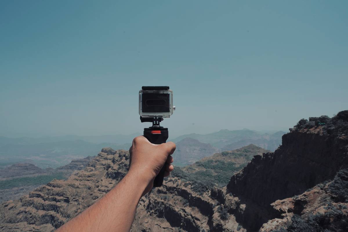 Backpacker using lightweight outdoor adventure camera on mountain trail