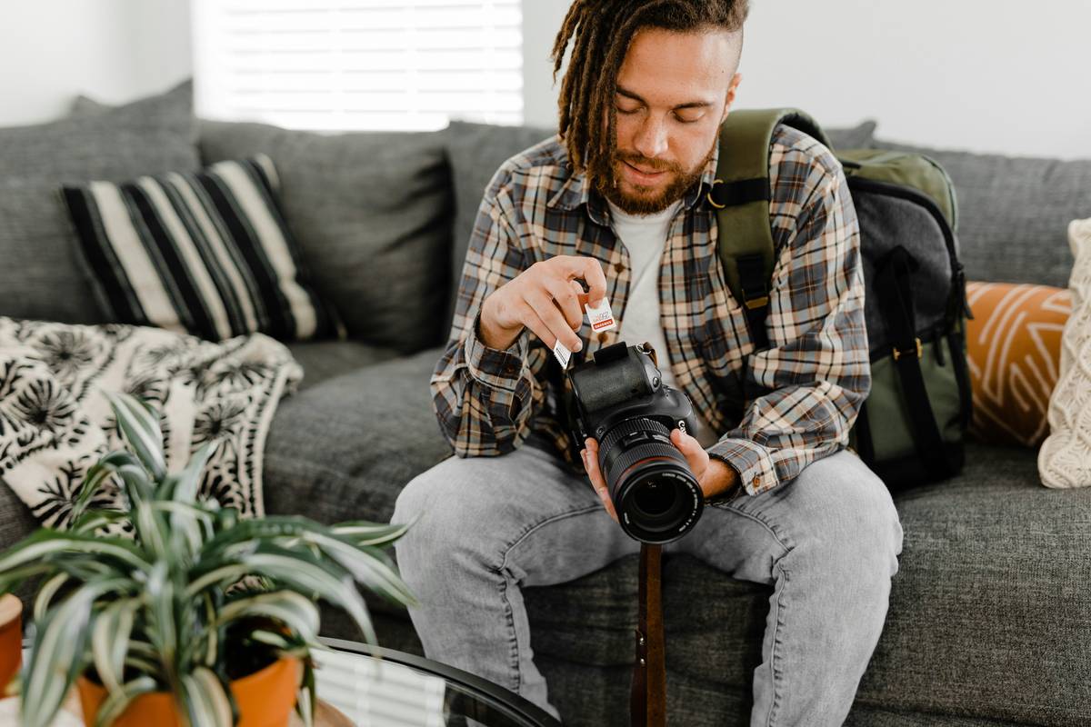 Landscape Camera Settings example showing a hiker adjusting aperture on a mirrorless camera overlooking mountains